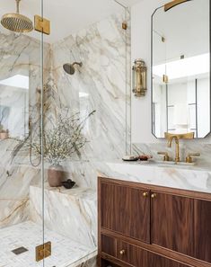 a bathroom with marble counter tops and gold fixtures on the shower wall, along with a wooden cabinet