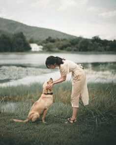 a woman petting a dog on the side of a lake