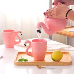 a person pouring water into pink flamingo mugs on a tray with lemons