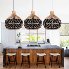 three lights hanging over a kitchen island with stools