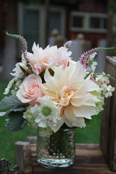 a vase filled with pink and white flowers on top of a wooden table in the grass