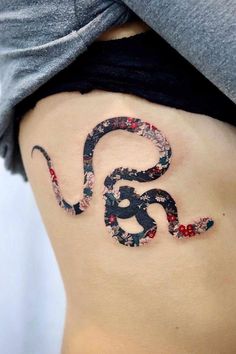 a snake tattoo on the side of a woman's stomach, with flowers all over it