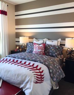 a baseball themed bed in a bedroom with striped wallpaper and red accents on the headboard