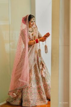 a woman in a pink and white bridal gown is holding an item with her hand