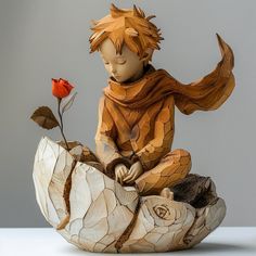 a wooden sculpture of a boy sitting on a rock with a flower in his hand