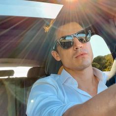 a man sitting in the back seat of a car with sun shining through his sunglasses