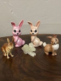 four small plastic rabbits sitting on top of a wooden table