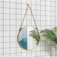 a mirror hanging on the wall next to a potted plant