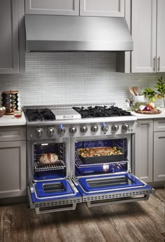 two open ovens in a kitchen with white cabinets and wood flooring on the walls