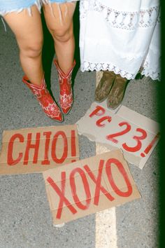 two people standing next to each other on the ground with signs in front of them