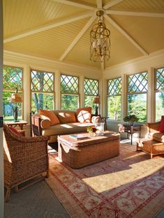 a living room with wicker furniture and large windows on the side of the wall