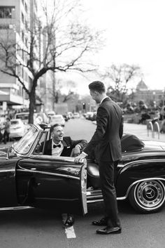 a man in a suit standing next to a car