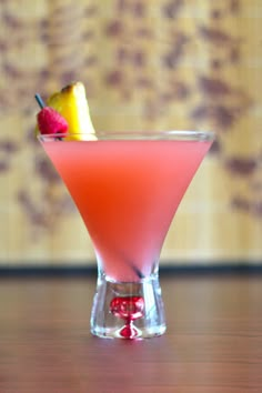 a pink drink with a slice of fruit on the rim and garnish in it