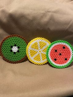 three pieces of beaded fruit sitting on top of a bed