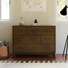 a room with a dresser, lamp and pictures hanging on the wall next to it