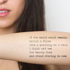 a woman with a tattoo on her arm that says, if the world could remain within a frame like a painting on a wall, i think we see the beauty then and stand staring in awe