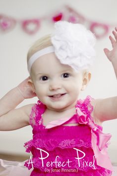 a baby girl wearing a pink dress and white headband