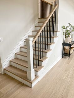 a white staircase with wooden handrails and black railing in a home's living room