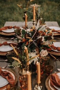 the table is set with candles, plates and napkins for an elegant fall dinner