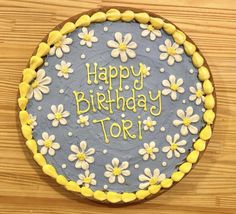 a birthday cake with the words happy birthday toi on it and daisies around the edges