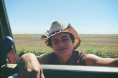 a young man wearing a cowboy hat sitting in the back of a truck