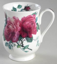 a white cup with pink roses painted on it