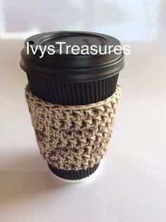 there is a coffee cup holder made out of crocheted yarn and has a black lid