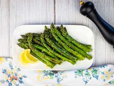 asparagus on a white plate with lemon wedges