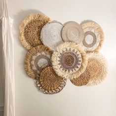 several woven baskets are hanging on the wall next to a white chair and rugs