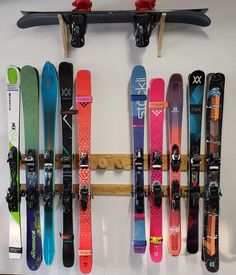 there are many skis hanging on the wall and in front of it is a snowboard rack