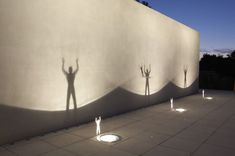 the shadow of a person standing in front of a wall with several lights on it