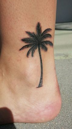 a small palm tree tattoo on the side of a woman's foot is shown