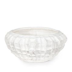 a white bowl with ruffles on the bottom and sides, sitting on a white surface