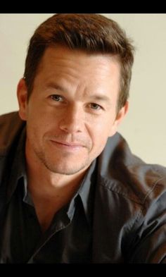 a close up of a person wearing a black shirt and looking at the camera with a serious look on his face