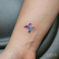 a small purple and blue butterfly tattoo on the left ankle, which is attached to a woman's wrist