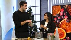 a man and woman standing in front of a table with christmas decorations on top of it