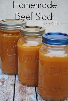 three jars filled with homemade beef stock sitting on top of a wooden table next to each other