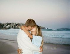 two people hugging each other on the beach