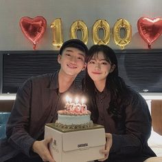 a man and woman sitting next to each other with a birthday cake in front of them