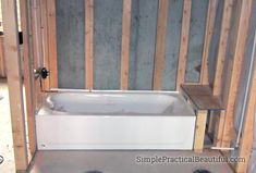 a bathtub sitting in the middle of a room with wooden framing on the walls