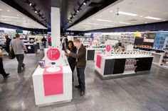 a man and woman standing in front of an electronic device display at a retail store