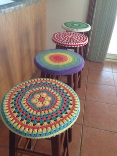 three crocheted stools sitting on top of a tile floor next to a counter