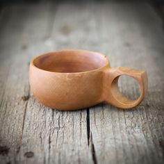 a small wooden bowl sitting on top of a wooden table next to a cup holder