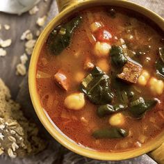 a yellow bowl filled with soup next to some bread