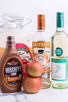 an assortment of alcohol bottles and apples on a counter