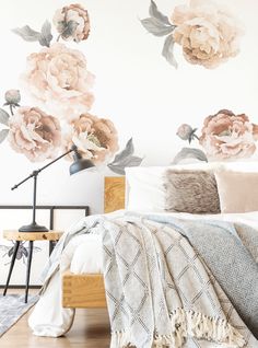 a bed room with a neatly made bed and flowers on the wall