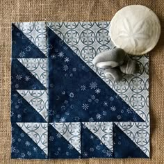 a blue and white patchwork quilt on the floor next to a gray stuffed animal