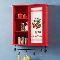 a red cabinet is hanging on a blue wall with spices and spice jars in it