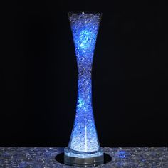 a tall blue vase sitting on top of a table next to a black wall and floor