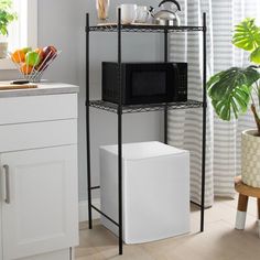 a kitchen with white cabinets and black shelving unit next to a potted plant